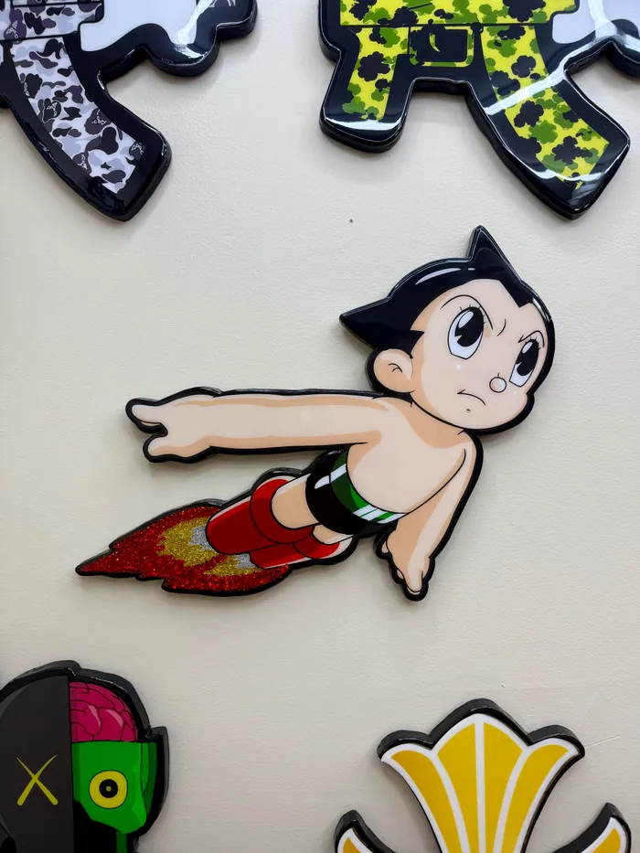 A flying cartoon boy with a red glitter rocket flame, in glossy epoxy on a wall
