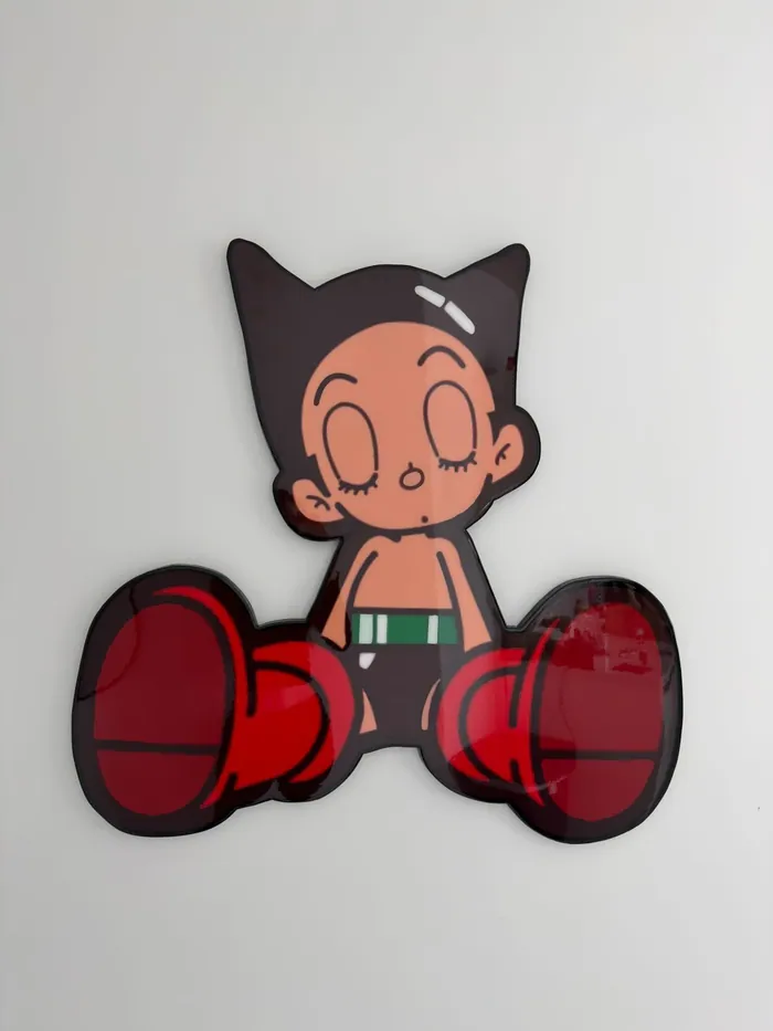 A cartoon boy with big red boxing gloves in glossy epoxy on a white wall