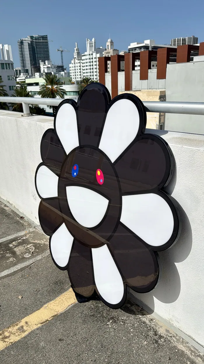 A black smiling flower piece against a Miami skyline